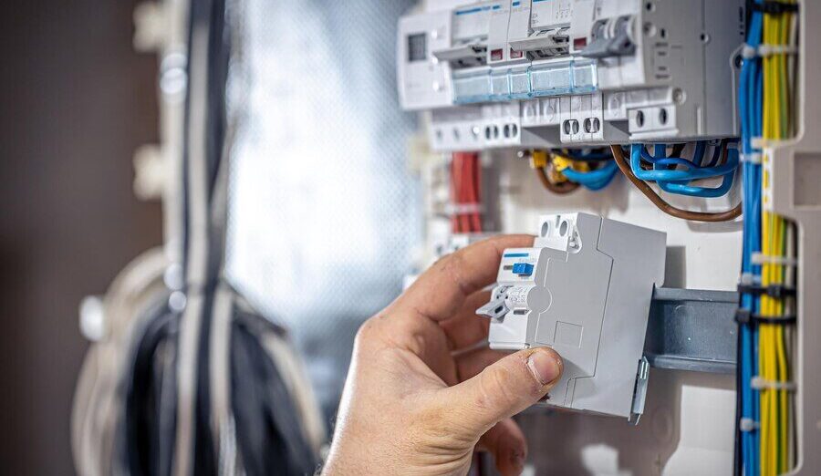 male-electrician-works-switchboard-with-electrical-connecting-cable_169016-16570